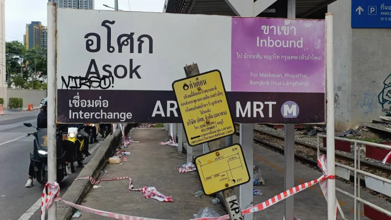 ป้ายสถานีอโศกและป้ายเตือน 'ห้ามจอดคร่อมรางรถไฟ' ที่ได้รับความเสียหาย